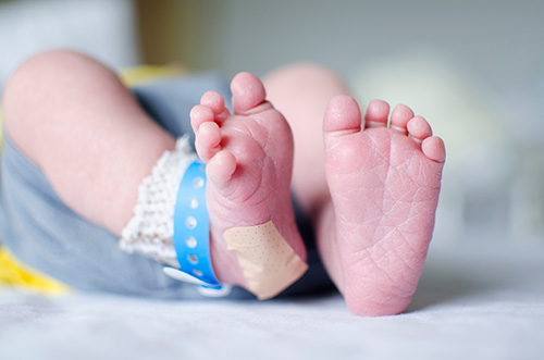 Newborn feet with heel test and band aid.